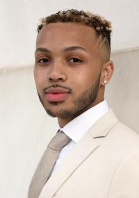 Headshot photo of a young man in a white suit